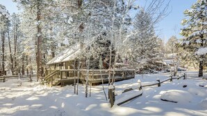A wooden cabin surrounded by snow-covered trees in a forest. - Munds Park Cabin w/ Deck & Fire Pit: Walk to Trail (Munds Park)