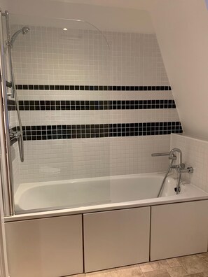 A modern bathroom with a freestanding bathtub, a glass-enclosed shower, and a tiled backsplash with black and white tiles.