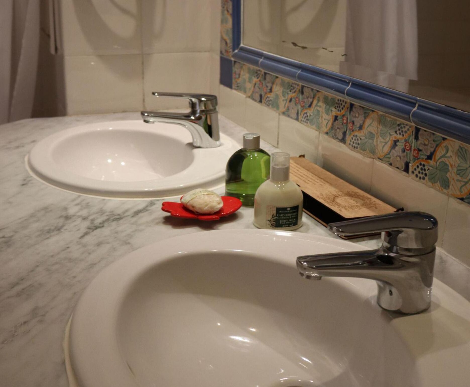 A bathroom with two sinks, a mirror, and a decorative tile backsplash.
