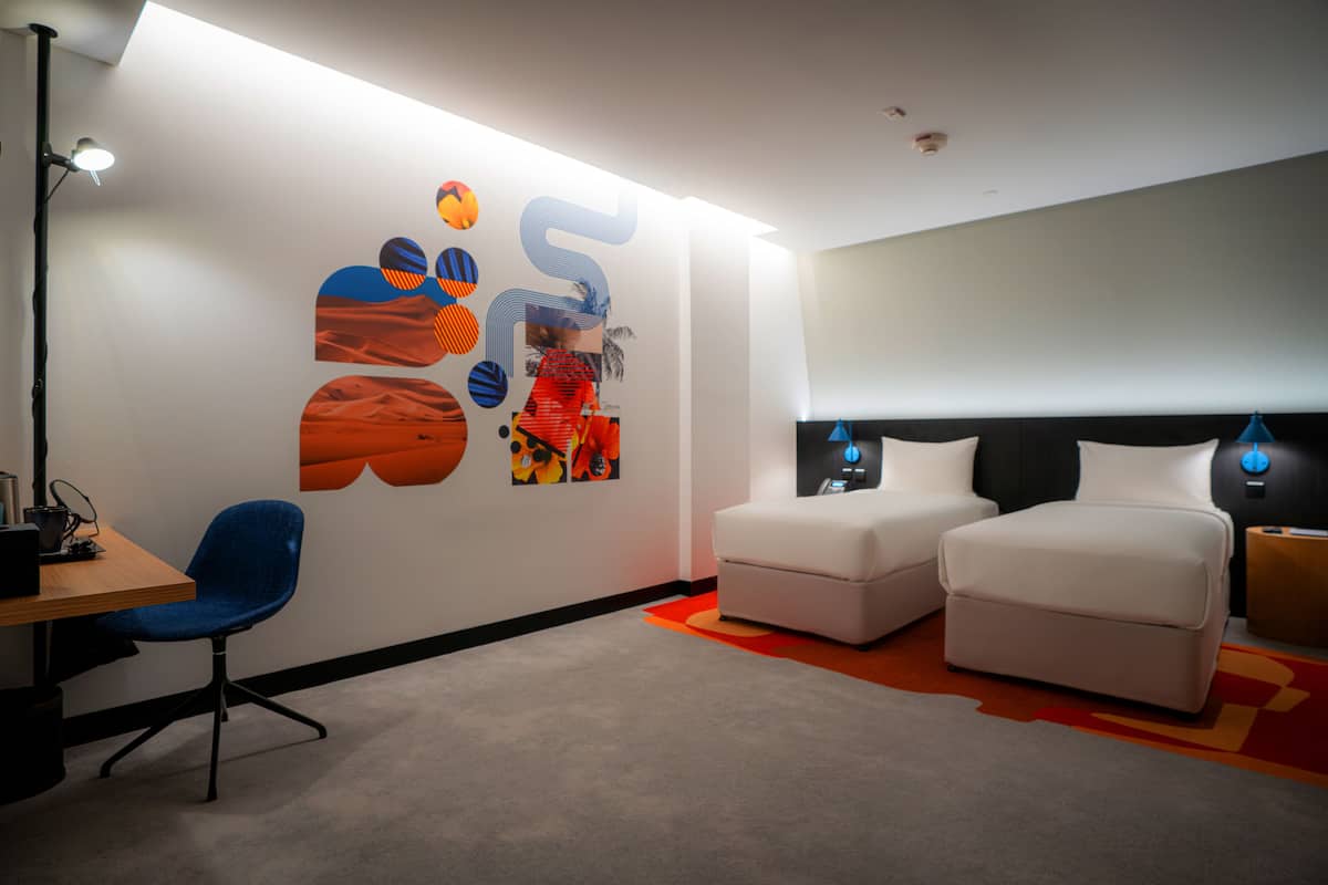 Una habitación moderna con un escritorio, dos sofás blancos y una silla azul.