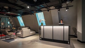 Un interior moderno con mostrador de recepción, zona de estar y un ventanal grande.