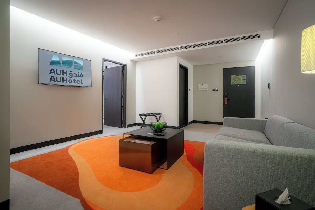 Un vestíbulo de hotel con una recepción, un sofá, una mesita de café y un cartel de AUH Hotel.