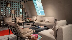 Una sala de estar moderna con techo alto, tragaluz inclinado y sofá modular.