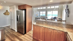 Eine Küche mit Holzausstattung, einer Arbeitsplatte aus Granit und einem Edelstahlkühlschrank.