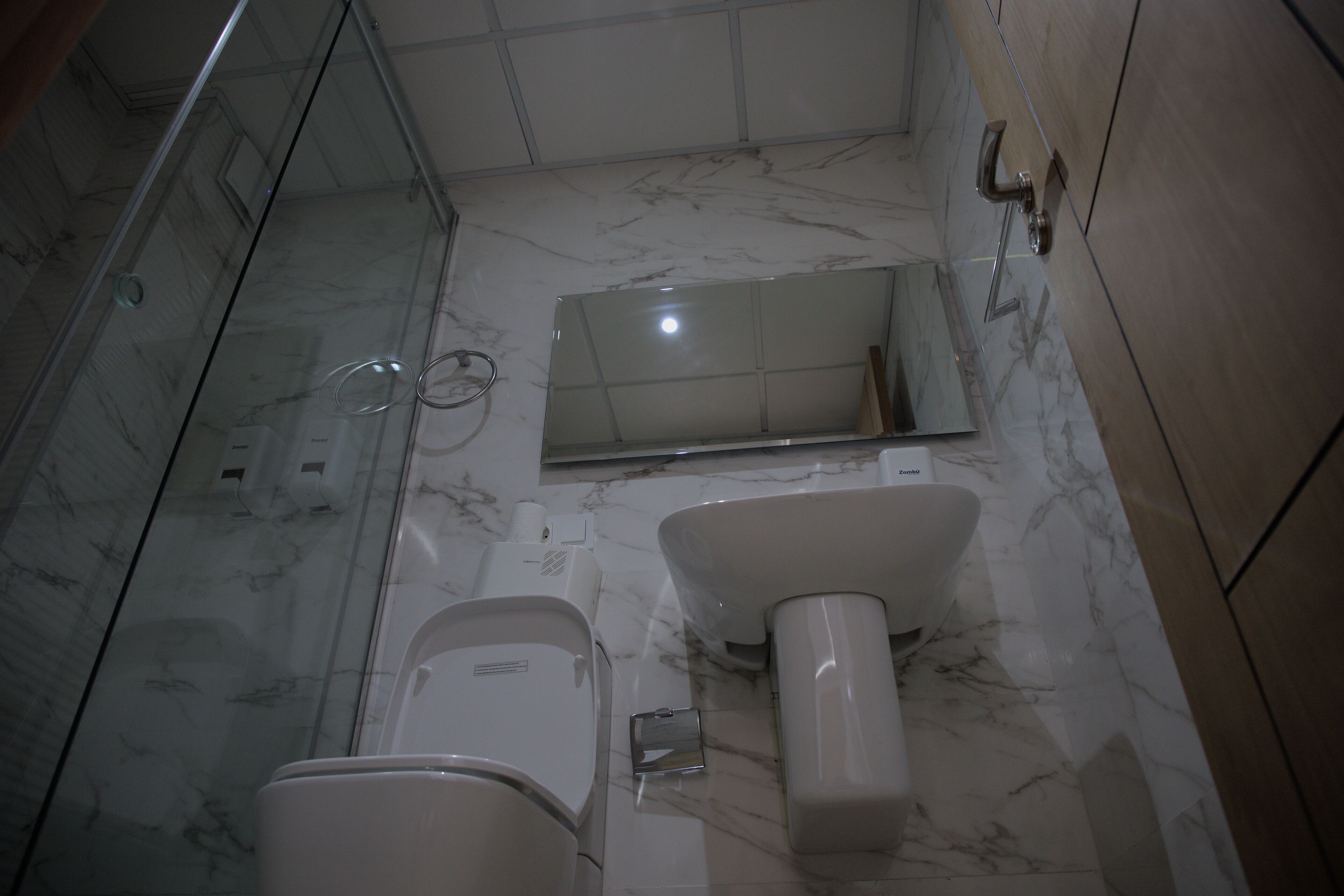 A bathroom with a toilet, a sink, and a mirror.