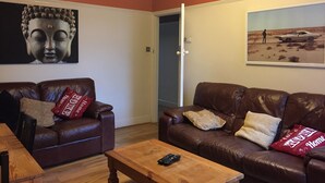 A living room with two brown leather sofas, a wooden coffee table, and a Buddha statue on the wall. - nifty two bed urban flat near leafy park and city (Gateshead)