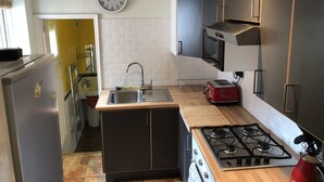 A compact kitchen with a sink, stove, and microwave. - nifty two bed urban flat near leafy park and city (Gateshead)