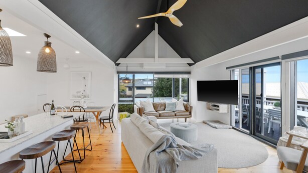 Una sala de estar moderna con techo alto, comedor y un gran ventanal con vistas al exterior.