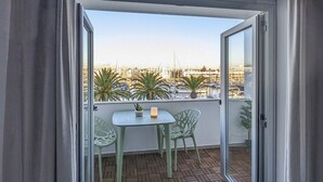 A balcony with a table and chairs, a potted plant, and a view of a marina with boats. - Captain's Quarters at Lagos Marina (Lagos)