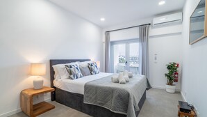A modern bedroom with a bed, bedside lamp, and a view of the city through a large window. - Captain's Quarters at Lagos Marina (Lagos)
