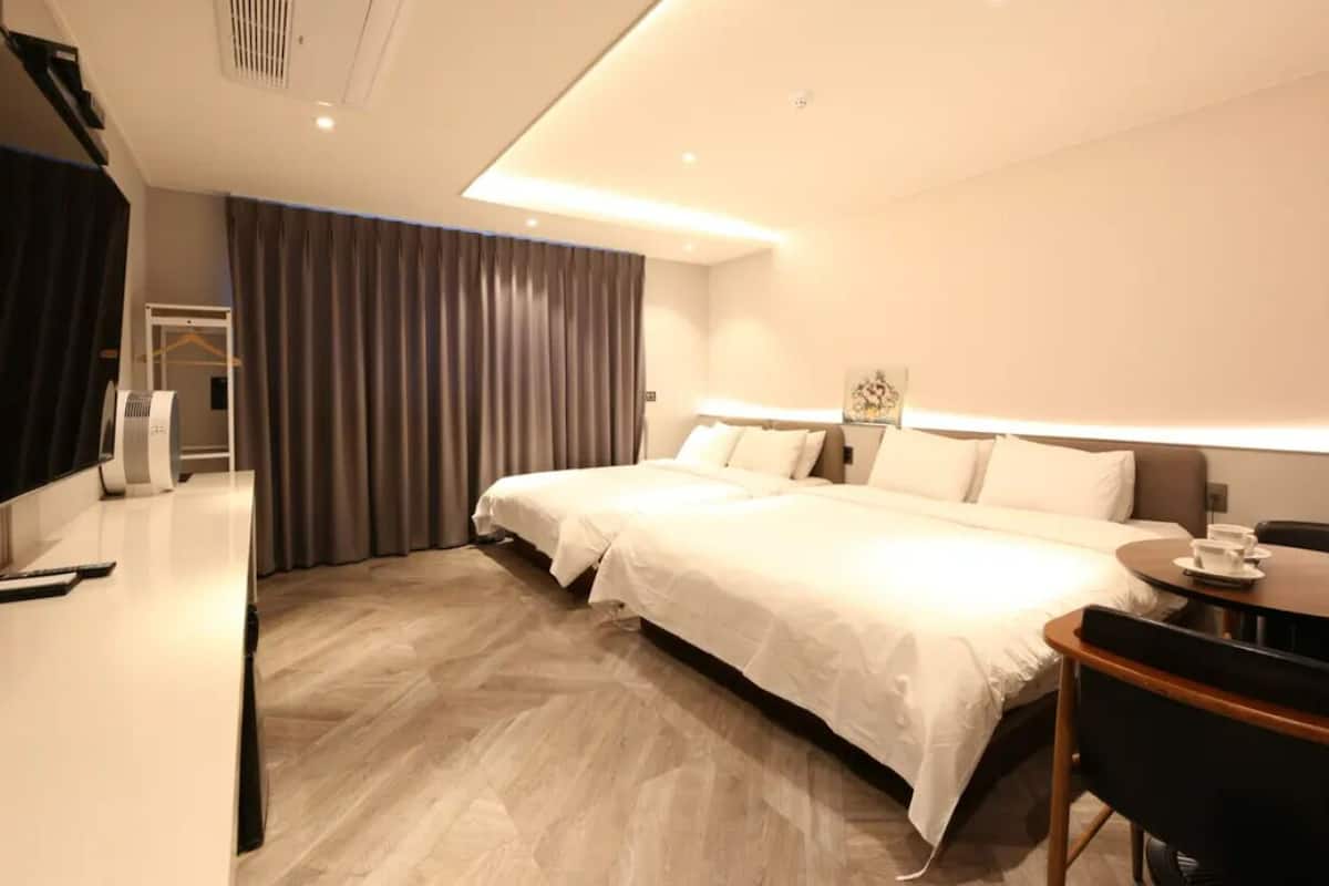 Une chambre d’hôtel avec un lit double, un bureau avec une chaise, une table de chevet et une lampe.