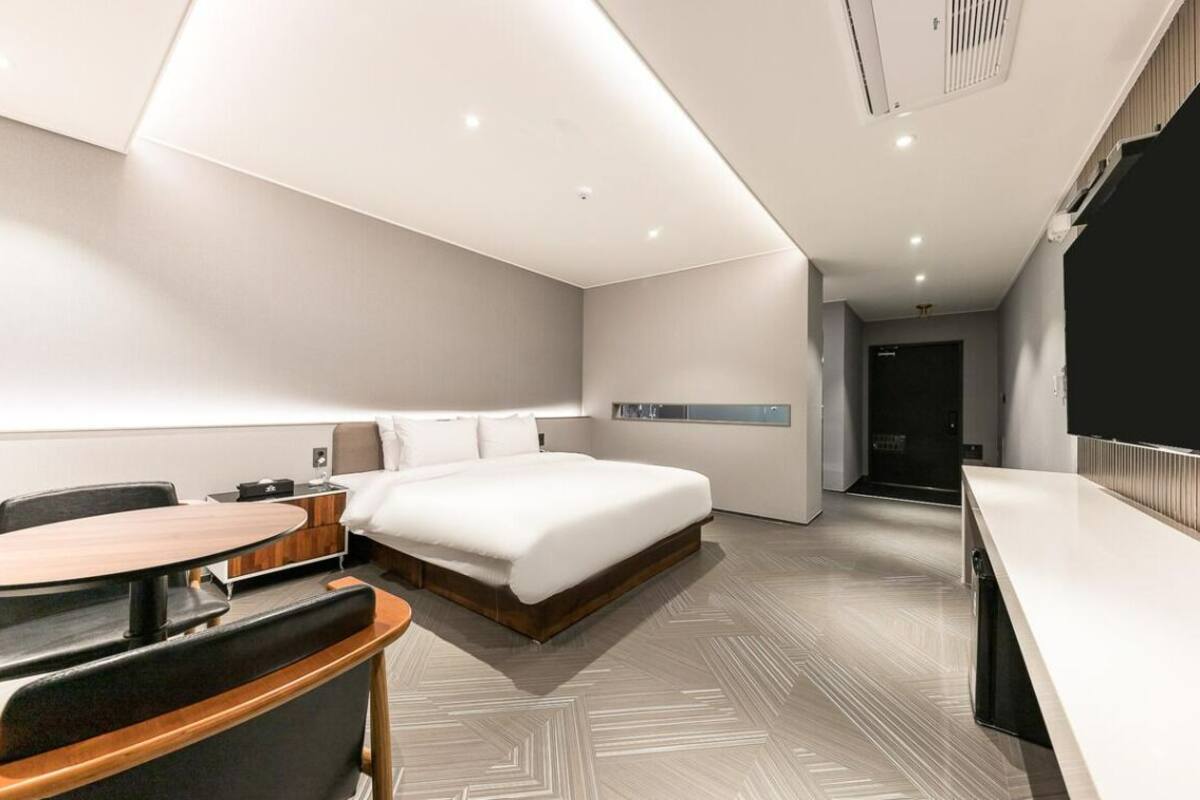 Une chambre d’hôtel moderne avec un grand lit, une table à manger et un petit coin cuisine.