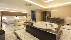 A modern hotel room with a large oval bathtub, a sofa, a bed, and a small table. - Gyeongju H Avenue Hotel Bulguksa (Gyeongju)