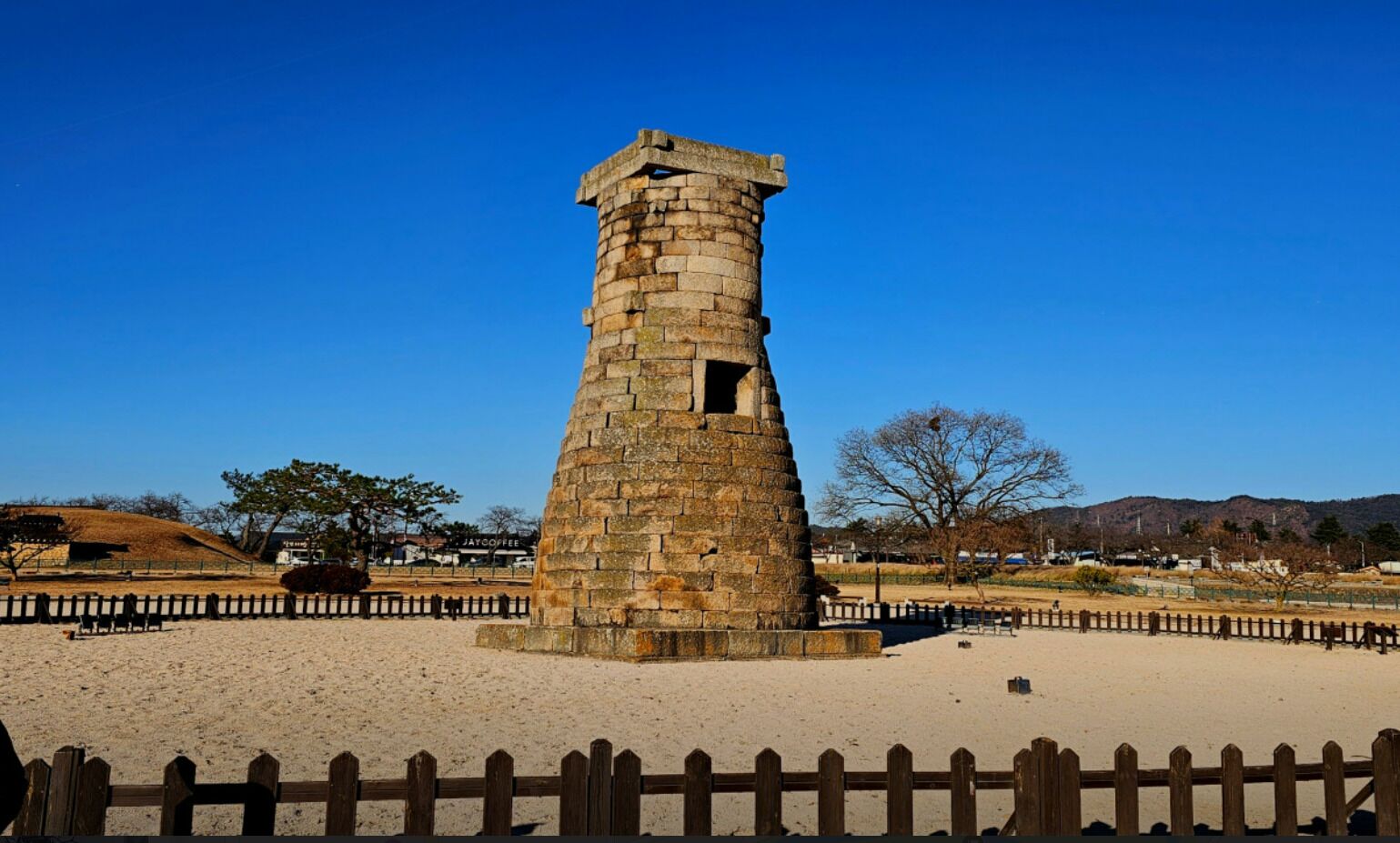A stone tower with a wooden fence in the foreground.
