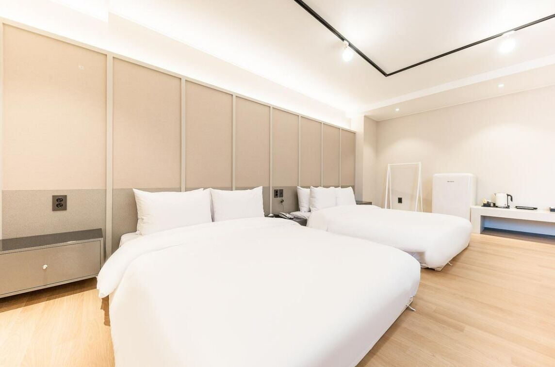 Habitación de hotel moderna con dos camas, un espejo grande, una mesita de noche y un armario empotrado.