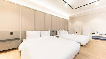 Habitación de hotel moderna con dos camas, un espejo grande, una mesita de noche y un armario empotrado.