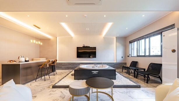 A modern living room with a central seating area, a built-in TV, and a large window. - Gyeongju H Avenue Hotel Bulguksa (Gyeongju)