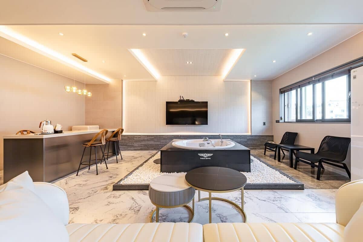 Un salon moderne doté d’un espace salon central, d’un téléviseur encastré et d’une grande fenêtre.