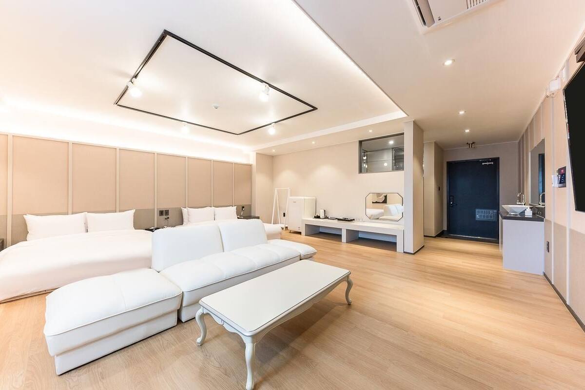 Une chambre d’hôtel moderne avec un grand lit, un canapé, une petite table et un bureau avec une chaise.