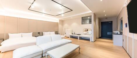 Habitación de hotel moderna con una cama grande, un sofá, una mesita y un escritorio con una silla.