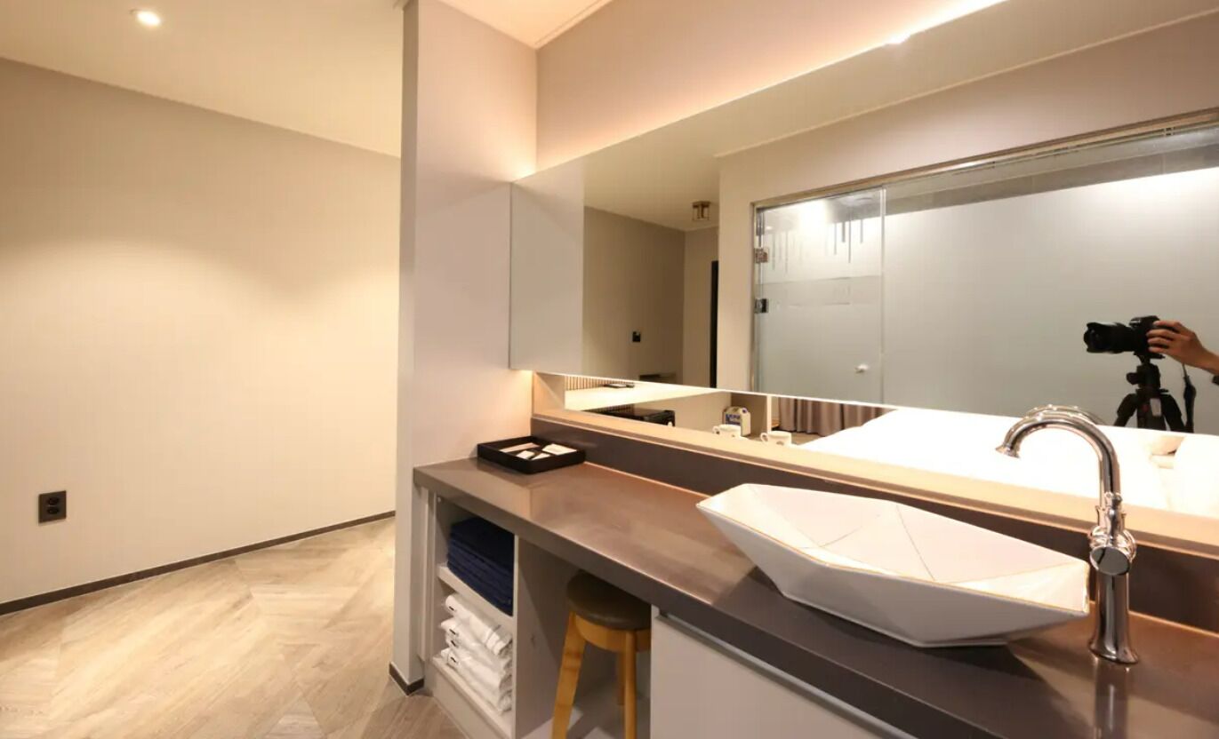 Un bagno moderno con uno specchio grande, un lavabo bianco e un mobile contenitore.