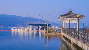 A pier with a traditional pavilion, boats docked, and a bridge in the background. - Gyeongju H Avenue Hotel Bulguksa (Gyeongju)