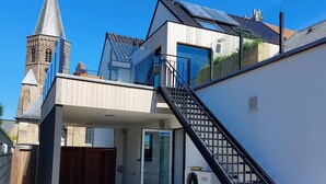 A modern house with a brick tower, a covered patio, and a staircase leading to a second floor. - b&b d'Ereplatse (Zuienkerke)