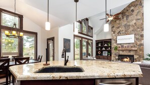A kitchen with a granite countertop, a stone wall, and a fireplace. - TRAI39 - Stunning Caldera Springs Home (Sunriver)