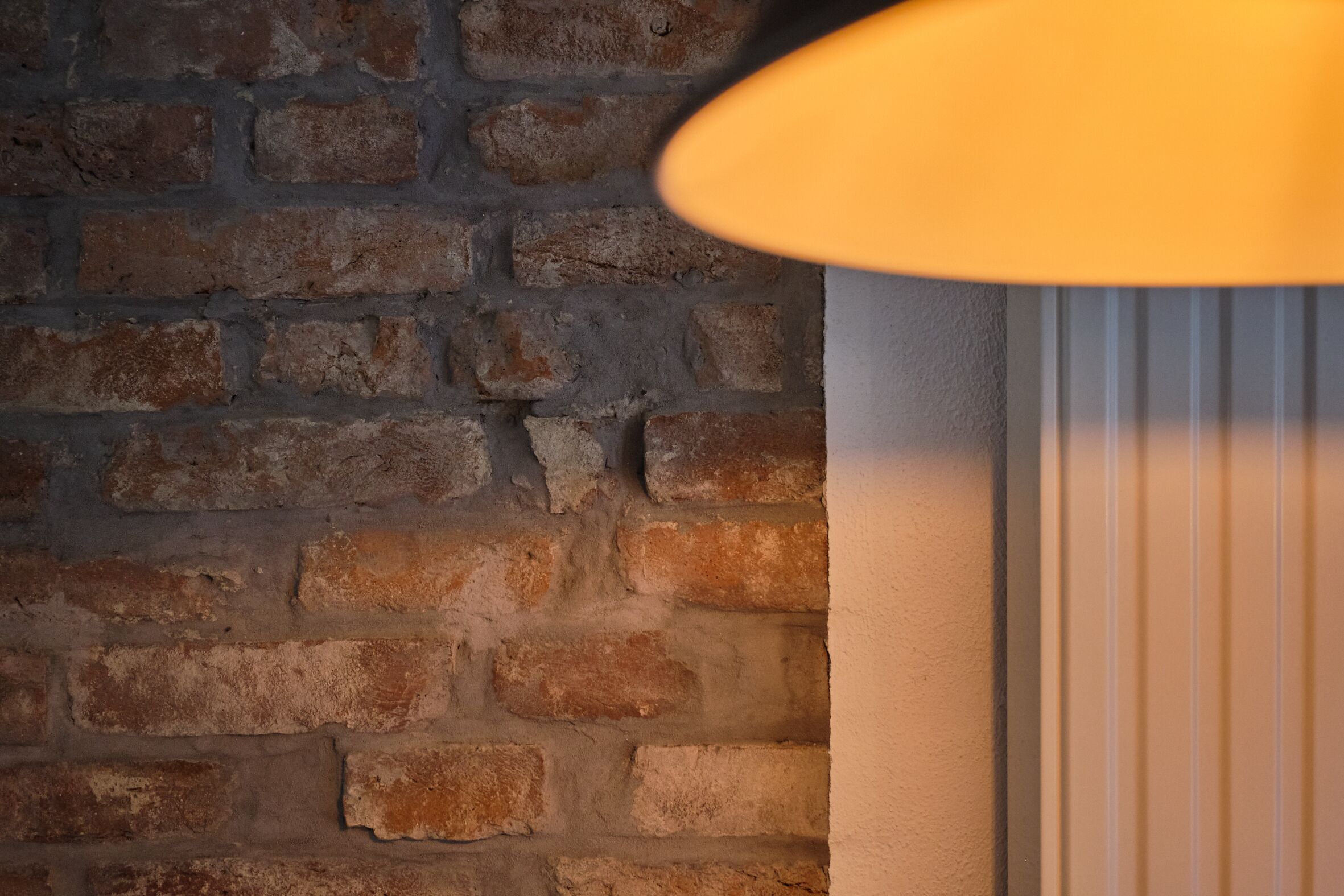 A brick wall with a textured surface and a white panel with vertical lines.