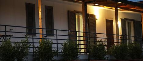 Un edificio con balcón, plantas en macetas y una pérgola de madera.