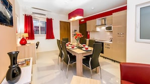 A modern dining area with a wooden table set for four, black chairs, and a red vase with flowers. - Blue 2: Two-Bedroom Apartment in St. Julian's (Swieqi)