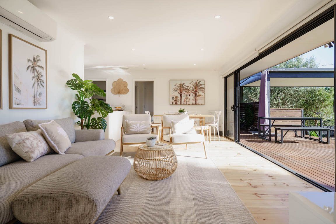 Ein geräumiger Wohnbereich mit Sofa, Couchtisch und Stühlen, ein Essbereich mit Tisch und Stühlen sowie eine Holzterrasse mit Sitzgelegenheit.