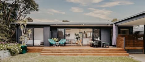 A modern house with a patio, outdoor seating, and a view of the backyard.