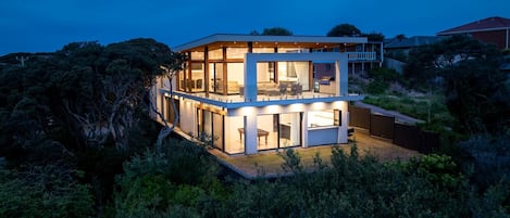 A modern two-story house with large glass windows and a balcony.