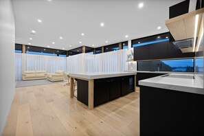A modern kitchen with a central island, black cabinetry, and a view of the outdoors.