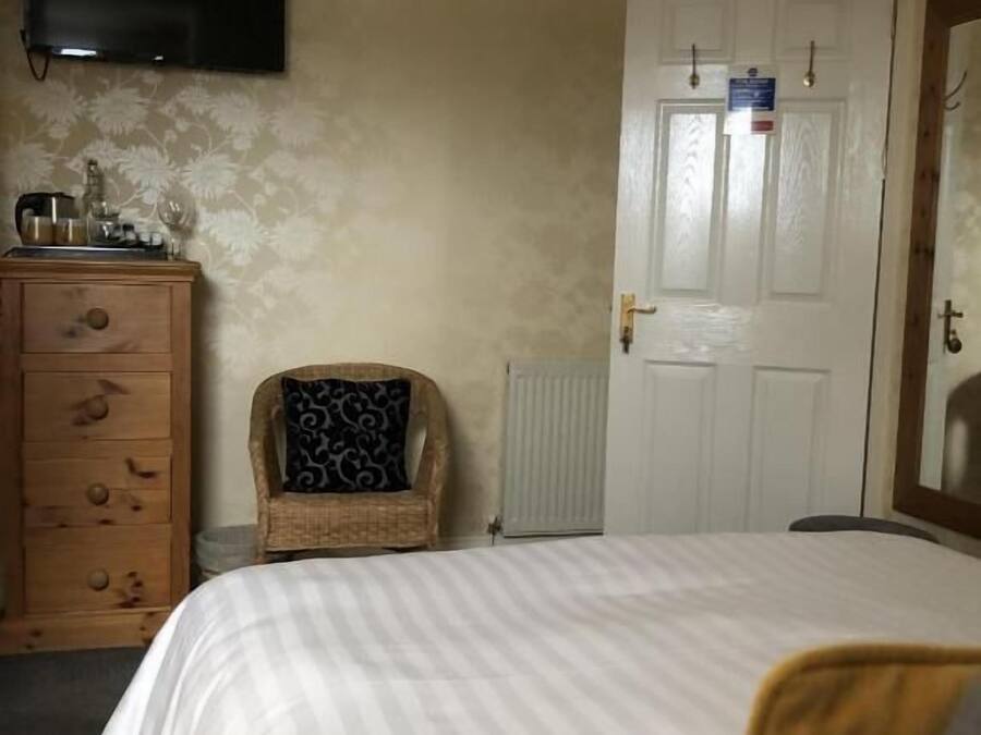 A bedroom with a bed, a dresser, a chair, a television, and a door with a sign.