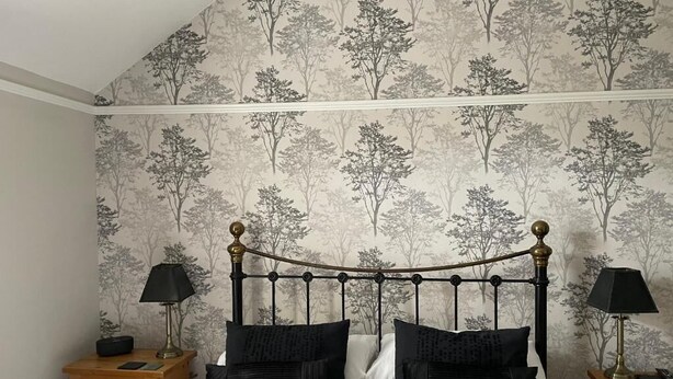 A bedroom with a bed, two nightstands, and a wall with a tree pattern. - Glendale Guest House (Keswick)