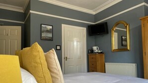 A bedroom with a bed, a television, a mirror, and a dresser. - Glendale Guest House (Keswick)
