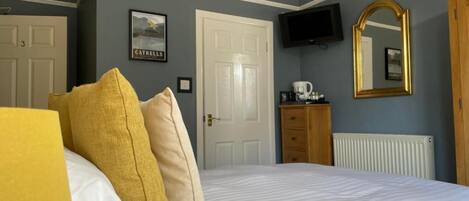 A bedroom with a bed, a television, a mirror, and a dresser.