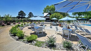 A poolside area with lounge chairs, umbrellas, and a patio with tables and chairs. - Comfortable 4 bedroom Townhome in Excellent Location, Bear Trap Dunes Community! Community Pool, Shuttle Service, WIFI, Golf, and more! (Ocean View)