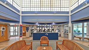A spacious lobby with a central reception desk, wooden benches, and a view of the outside through large windows. - Comfortable 4 bedroom Townhome in Excellent Location, Bear Trap Dunes Community! Community Pool, Shuttle Service, WIFI, Golf, and more! (Ocean View)