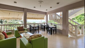 A spacious balcony with green seating, a dining area, and a staircase leading to an upper level. - Villa Matilda (Lukovë)