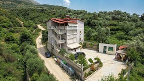 A multi-story building with a red-tiled roof, a balcony, and a paved courtyard. - Villa Matilda (Lukovë)