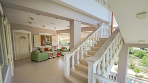 A spacious living area with a staircase, green sofa, and a view of the outdoors. - Villa Matilda (Lukovë)