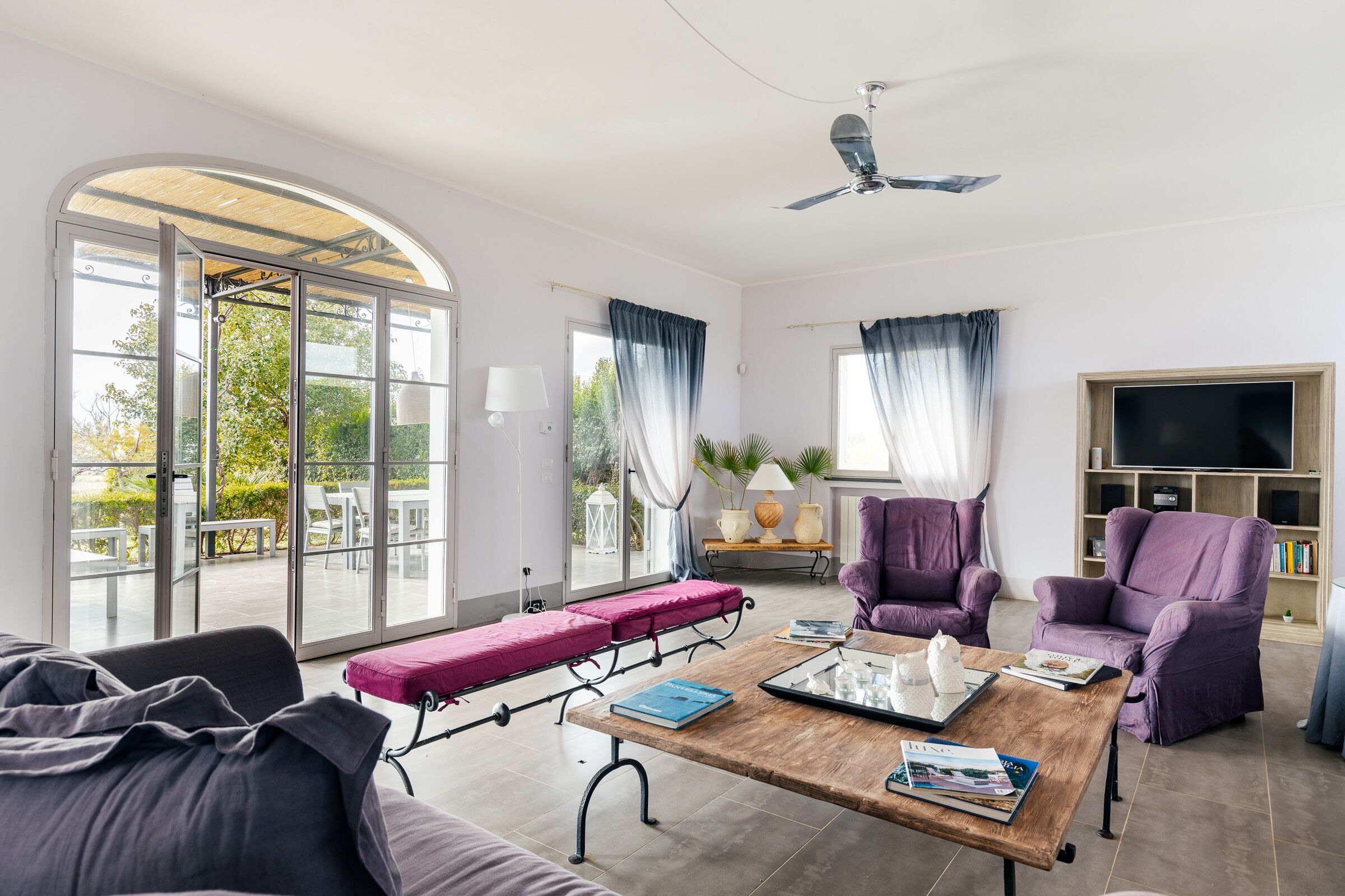 Un salón amplio con un sofá, una mesa de centro y dos sillones morados.