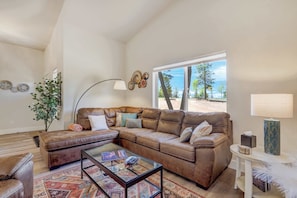 A living room with a brown leather sofa, a glass coffee table, and a view of the outdoors.