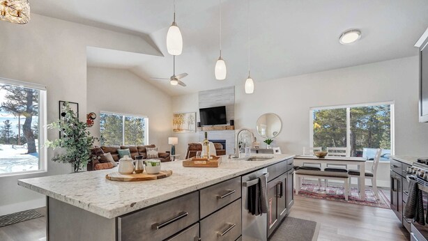 Cozinha moderna com uma ilha grande, luminárias pendentes e um espaço de jantar com vista.