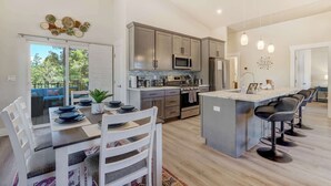 Cozinha moderna com eletrodomésticos de aço inoxidável, uma ilha grande com banquetas e uma área de jantar com vista.