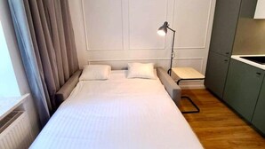 Et lille, pænt indrettet soveværelse med en seng, et natbord og en lampe.