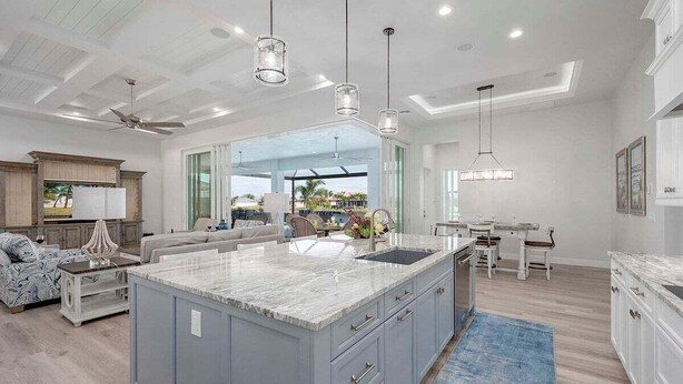 A spacious kitchen with a large island, modern pendant lights, and a view to the outdoors. - Mystique  - Luxury Waterfront Home (Cape Coral)